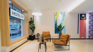 A hotel lobby with a sign reading 'HOTEL 99', a large abstract painting, a flag, and leather chairs.