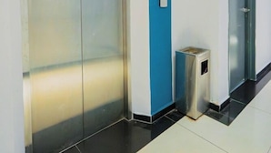 A hallway with a blue accent wall, a trash bin, and an elevator.
