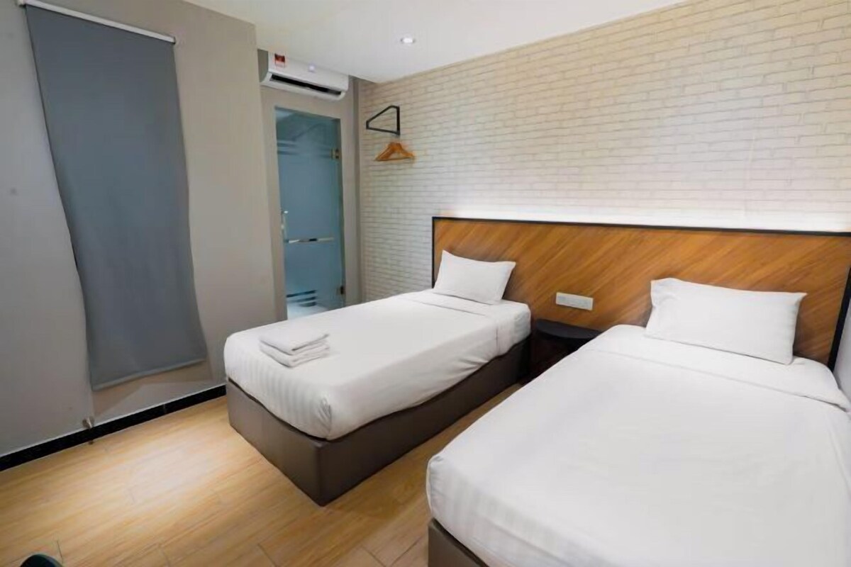 Une chambre d’hôtel avec deux lits, une armoire et un mur décoré d’un motif en briques.
