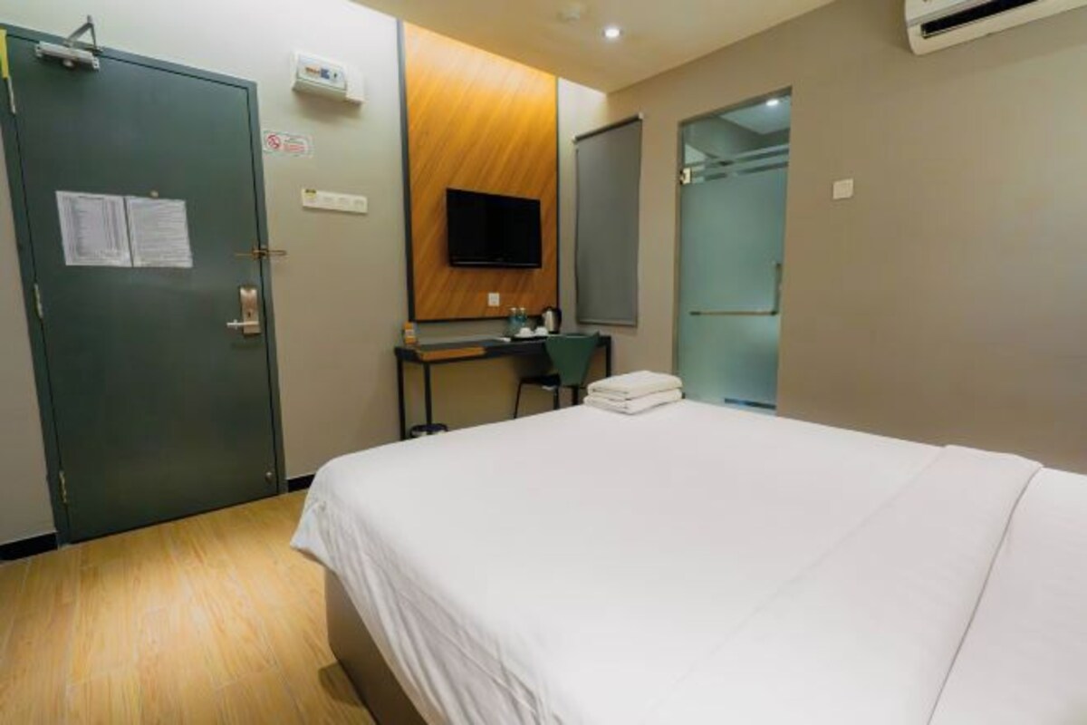 Una habitación de hotel con cama, escritorio, silla, televisor y armario.
