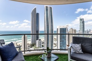Un balcon offrant une vue sur les grands immeubles et l’océan.