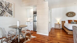 A modern, compact living space with a kitchen, dining area, and bedroom. - The Driftwood on Magazine (New Orleans)