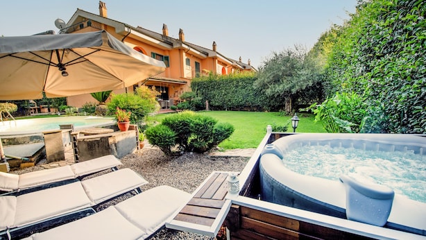 A backyard with a hot tub, lounge chairs, and a patio umbrella. - The Aurora's Nest (Belvedere Lidia)