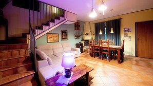 A living room with a staircase, a sofa, a dining table with chairs, and a lamp. - The Aurora's Nest (Belvedere Lidia)