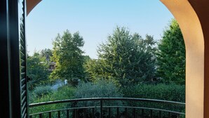 An open balcony with a curved railing, a view of a green lawn, and trees in the background. - The Aurora's Nest (Belvedere Lidia)