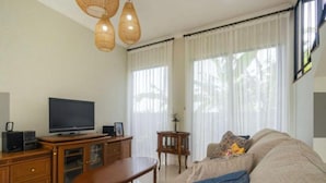 Una sala de estar con televisor, muebles de madera y un sofá.