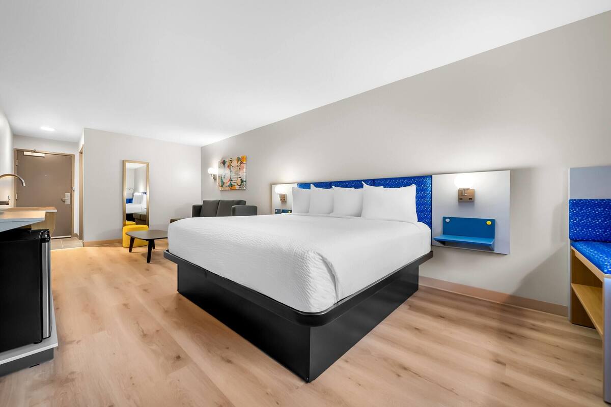 Quarto de hotel moderno com uma cama grande, uma escrivaninha e uma cadeira.