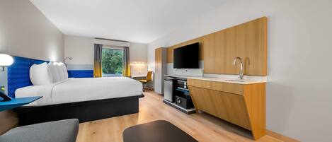 Una habitación de hotel moderna con cama, escritorio, televisor y baño.
