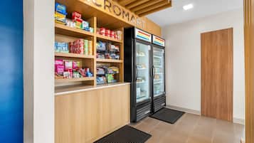 L’intérieur d’une épicerie, avec des étagères remplies de divers produits, un présentoir réfrigéré et un comptoir en bois.