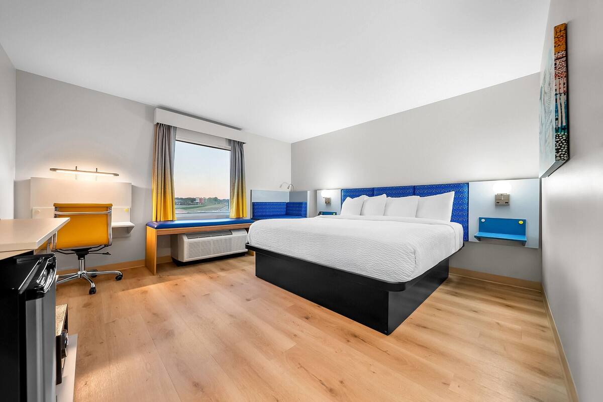 Quarto de hotel moderno com uma cama grande, uma escrivaninha e vista para a cidade.