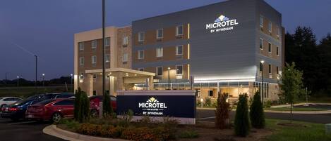 A Microtel Inn & Suites building with a parking lot and a landscaped area with shrubs and flowers.