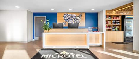 Et receptionsområde med et Microtel by Wyndham skilt, en receptionsdisk, HP computere, et kunstværk på væggen og en Microtel butik.