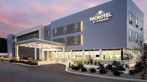 Un hotel Microtel moderno de Wyndham con entrada cubierta, zona de estar exterior y fachada bien iluminada.