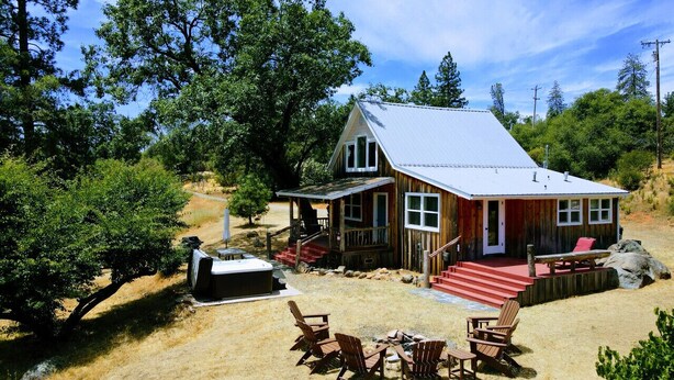 A wooden cabin with a porch, outdoor seating, and a hot tub. - Rare 12-Guest Cabins w/ Hot Tubs, Fire Pits & Pets (Mariposa)