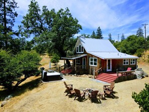A wooden cabin with a porch, outdoor seating, and a hot tub. - Rare 12-Guest Cabins w/ Hot Tubs, Fire Pits & Pets (Mariposa)