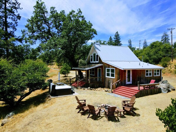 A wooden cabin with a porch, outdoor seating, and a hot tub.