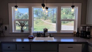 A kitchen with a large window, a coffee maker, and a dish soap dispenser.