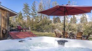 A hot tub with a wooden deck and outdoor seating. - Rare 12-Guest Cabins w/ Hot Tubs, Fire Pits & Pets (Mariposa)