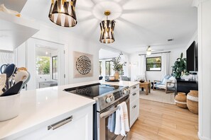 Cozinha moderna com ilha central, eletrodomésticos de aço inoxidável e iluminação pendente.