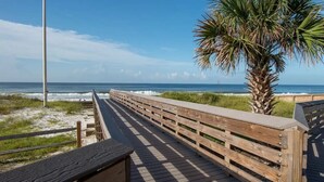 A wooden boardwalk leading to the beach with a palm tree and a flagpole. - Charming Blue Mountain Bungalow in 30A. Walk or Golf Cart down to the sand.  (Santa Rosa Beach)