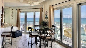 Una habitación con balcón, una mesa de comedor con sillas, un sofá y un ventilador de techo.