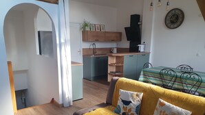 Una sala de estar moderna con un sofá, una mesa de centro y una zona de cocina al fondo.