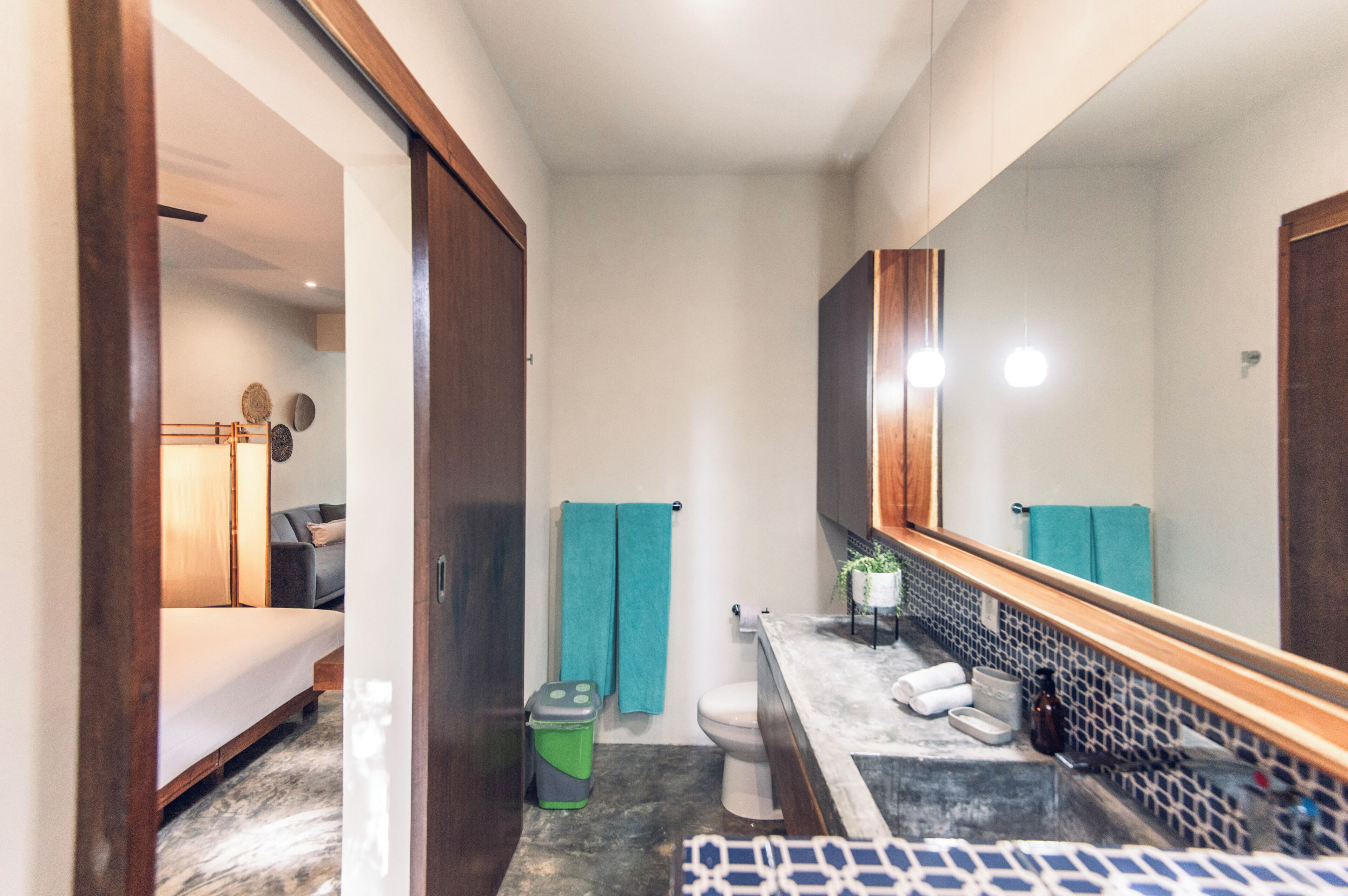 Un baño moderno con un espejo grande, un inodoro, un lavabo y una zona de ducha.