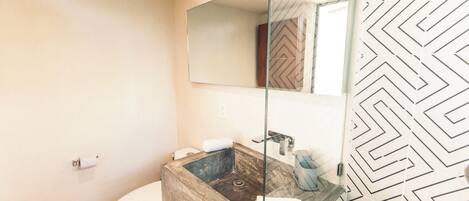 A bathroom with a wooden sink, a toilet, and a mirror.