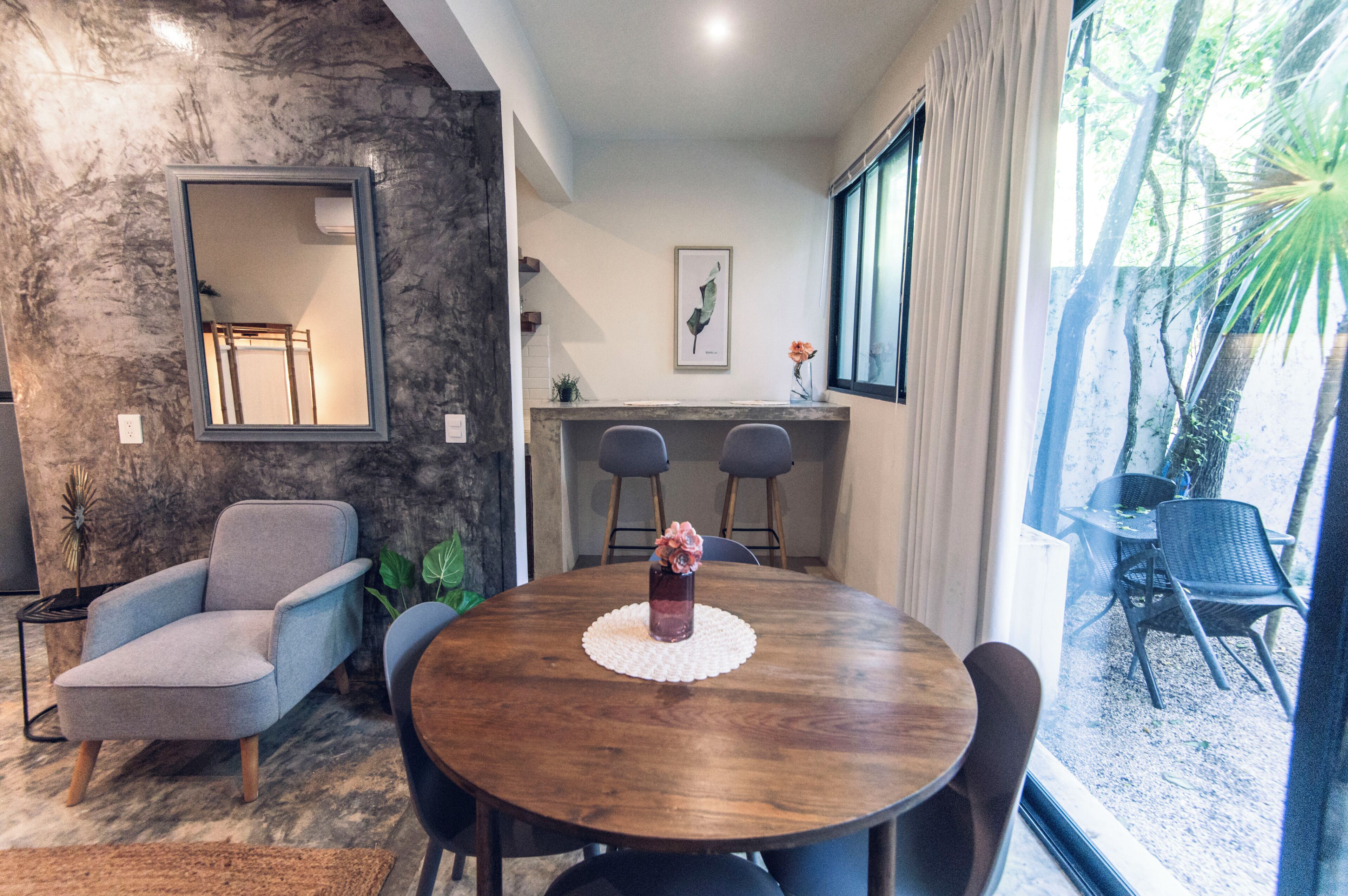 Un comedor moderno con una mesa de madera, sillas tapizadas en gris y un jarrón decorativo.