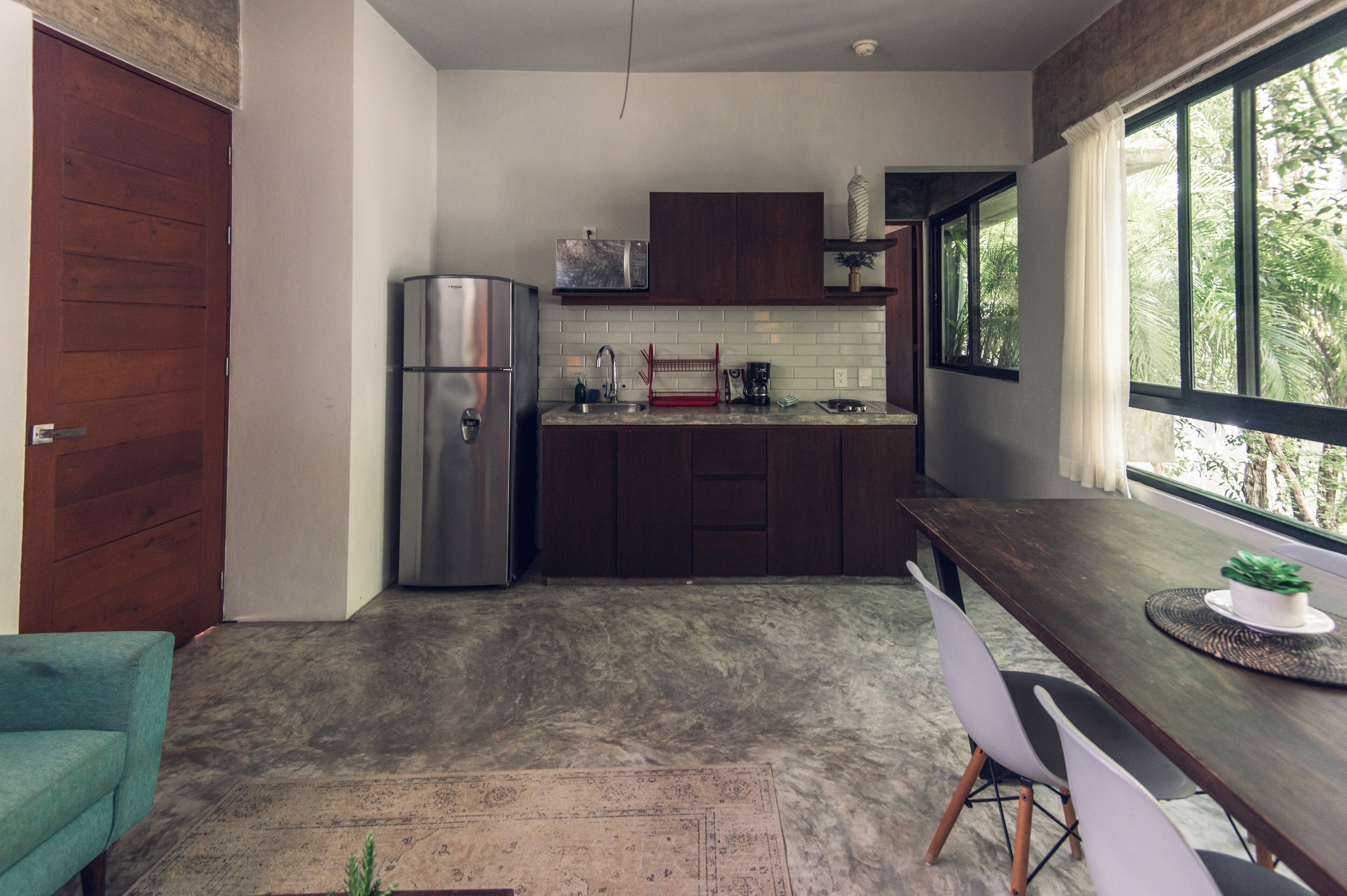 Una cocina moderna con armarios de madera oscura, un refrigerador de acero inoxidable y una ventana que ofrece vistas a zonas verdes.