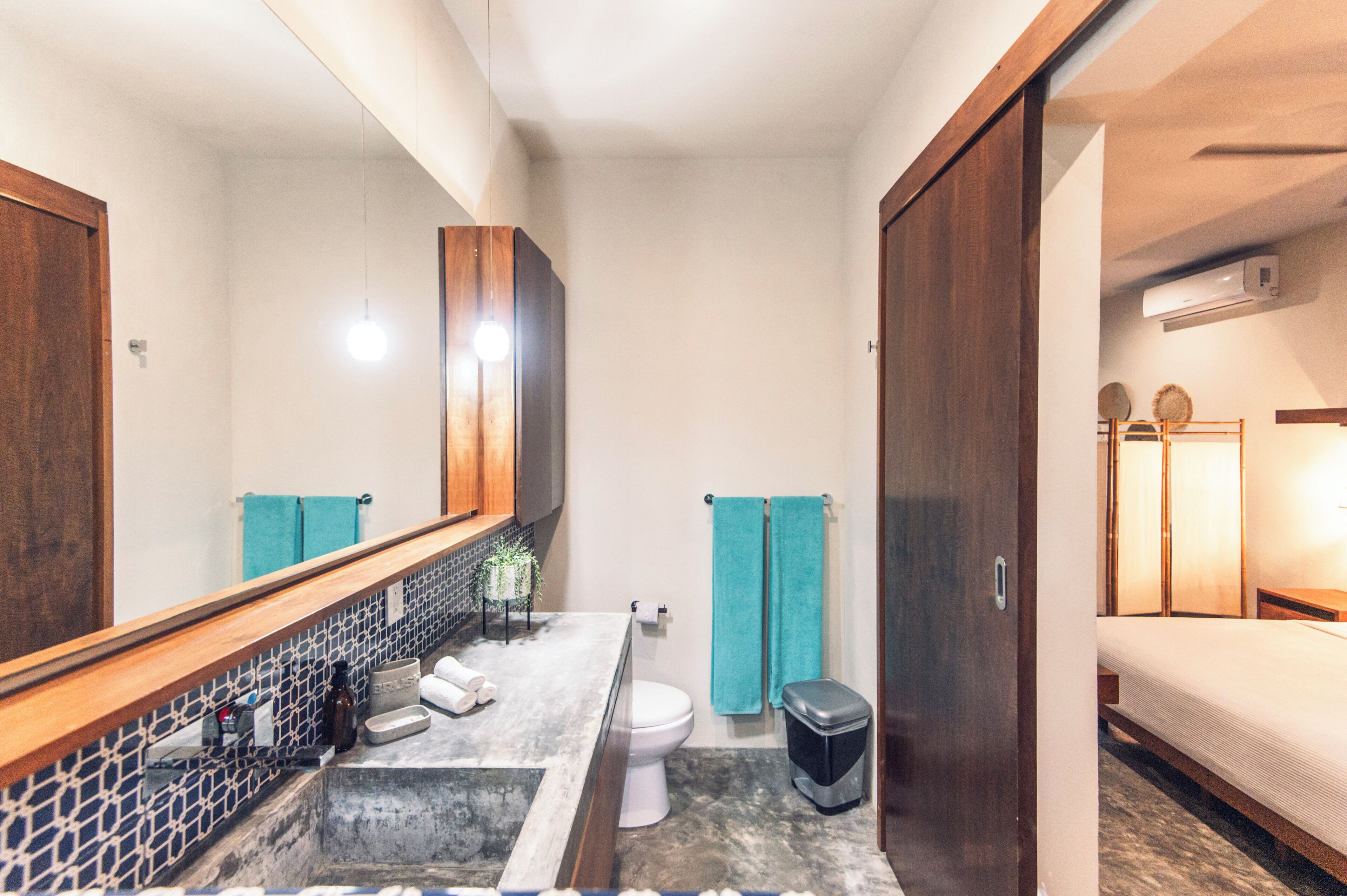 A bathroom with a large mirror, a sink, a toilet, and a shower area.