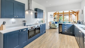 Una cocina moderna con gabinetes azules, horno empotrado y una isla grande con pileta.