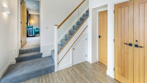 Una escalera con barandillas de madera y peldaños alfombrados que conduce a una habitación con un sofá color turquesa y una lámpara.