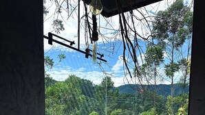 Kylpyläalue, jossa on poreallas, puinen terassi ja näkymä vehreään metsään ja vuorille.