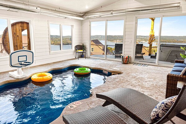 Una piscina interior con vistas del paisaje circundante, una silla y una mesa.