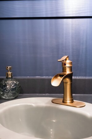 A bathroom sink with a gold faucet and a soap dispenser.