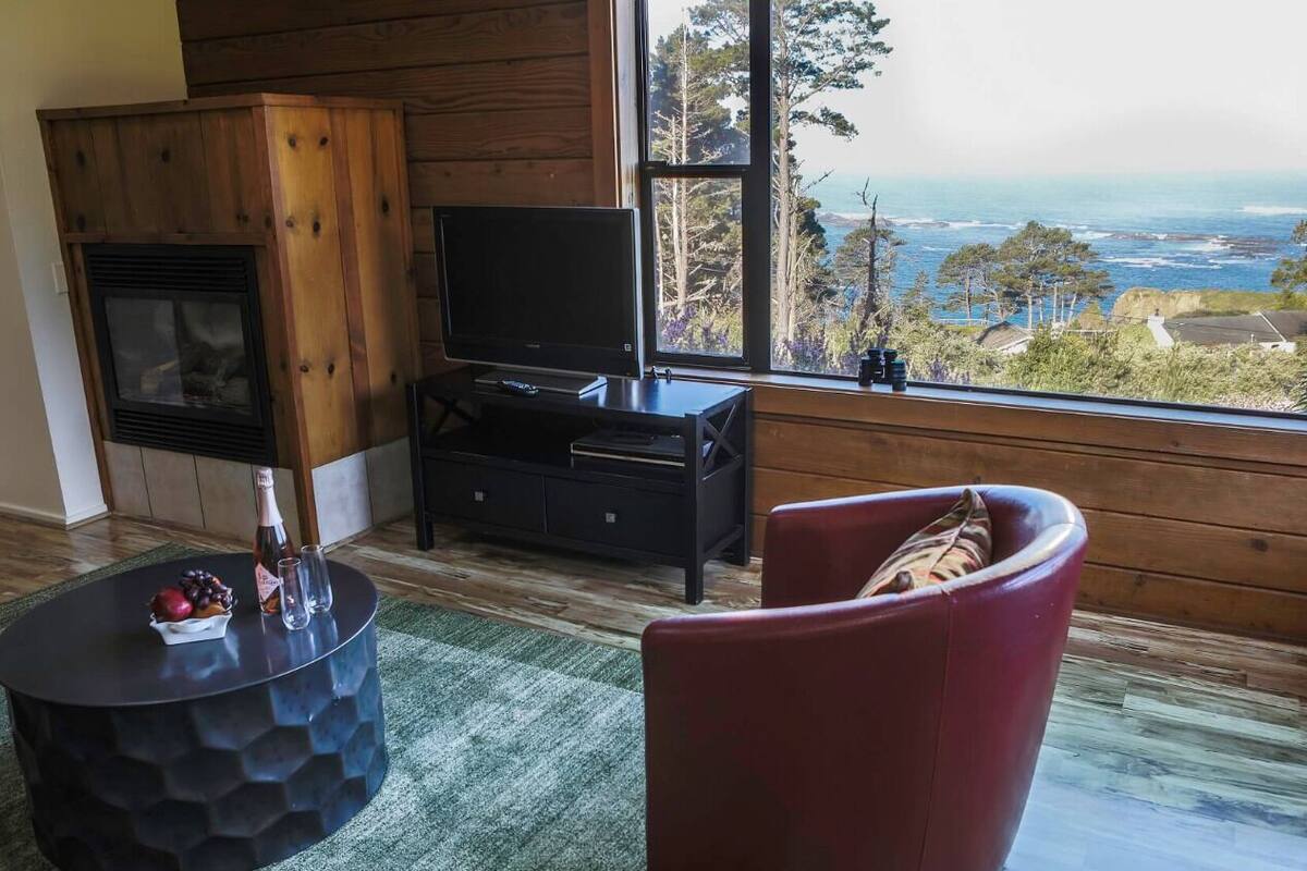 Una sala de estar acogedora con chimenea, televisor y un sillón rojo cómodo.