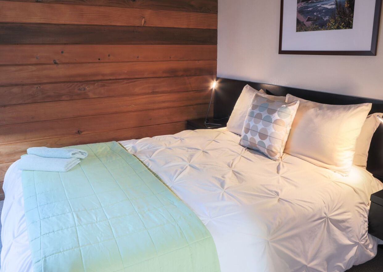 A neatly made bed with a quilt, pillows, and a folded towel.