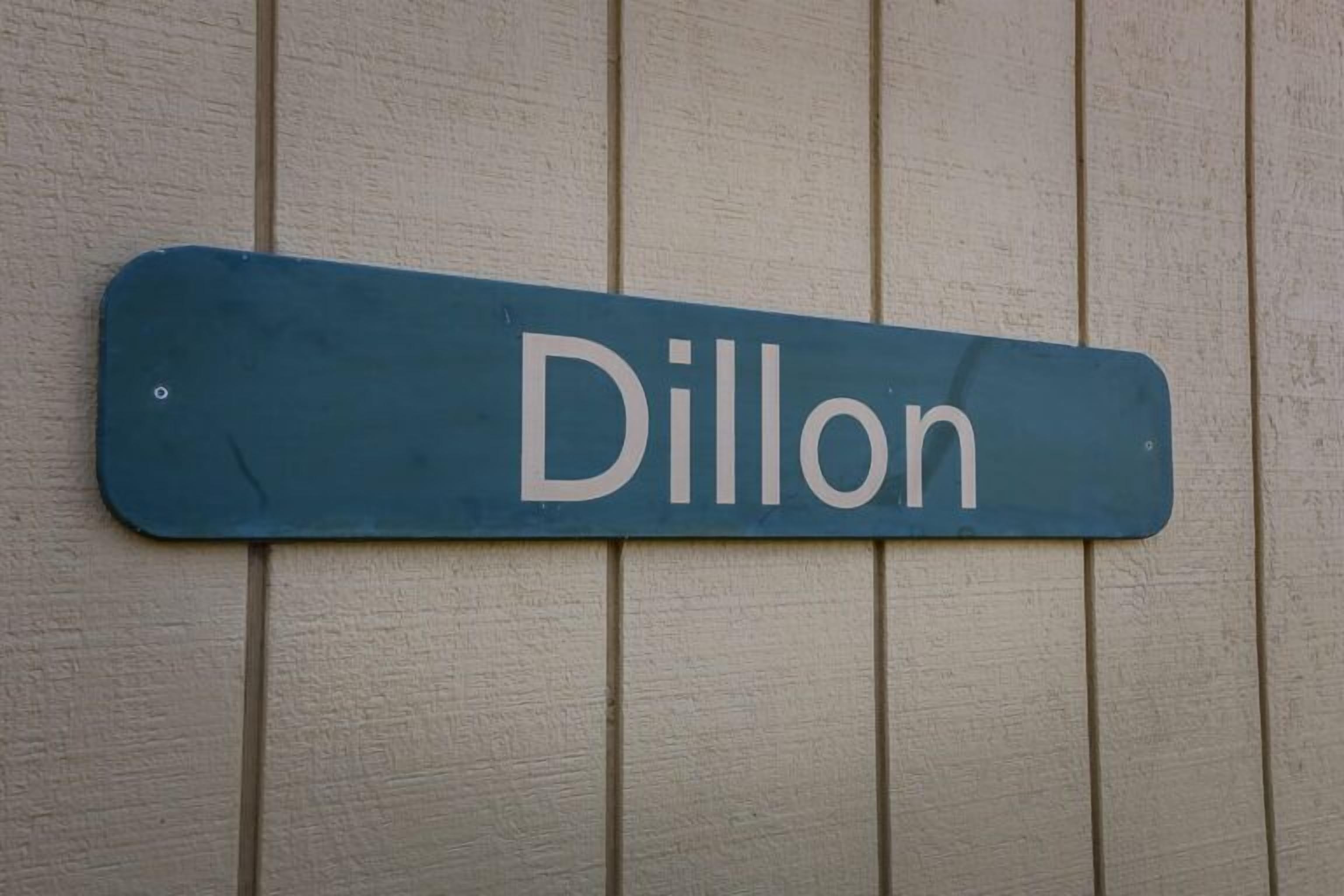A blue sign with the name "Dillon" on a textured wall.