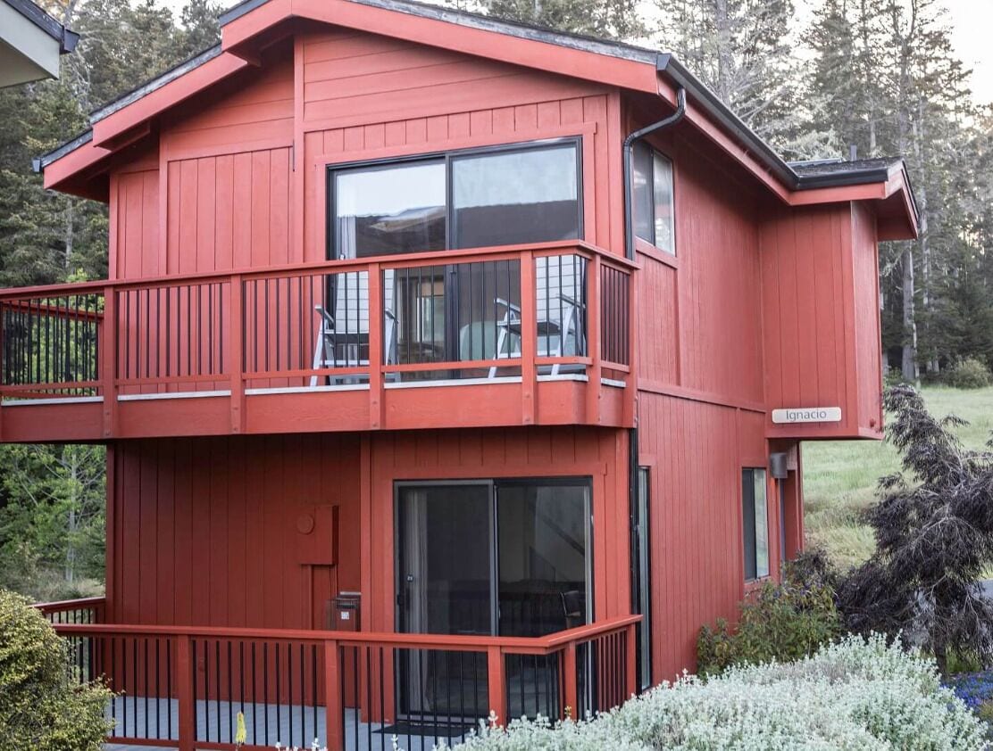 Een rood gebouw met twee verdiepingen, balkons en grote ramen.