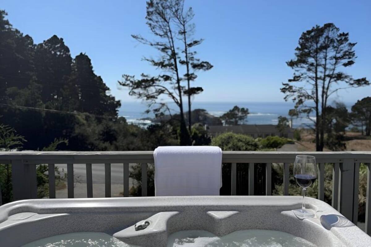 Un jacuzzi con una toalla al borde, con vista a un paisaje pintoresco del océano y árboles.