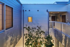 A modern building with a balcony, a small window, and a tree in front. - Reikyo Garden Osaka (Osaka)