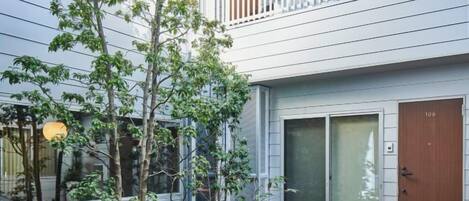A modern building with a large sliding glass door, a wooden door, and a balcony with a railing.