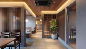A modern interior with wooden paneling, a central potted plant, and a dining area with wooden furniture. - Reikyo Garden Osaka (Osaka)