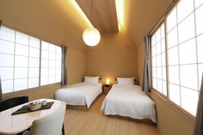 A hotel room with two beds, a small table with a chair, and a large window with curtains. - Reikyo Garden Osaka (Osaka)