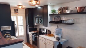 A modern kitchen with dark cabinets, stainless steel appliances, and decorative items on shelves. - Overlooking Amazing Pool, 2 King ensuite Condo, location, location, location! (Sedona)