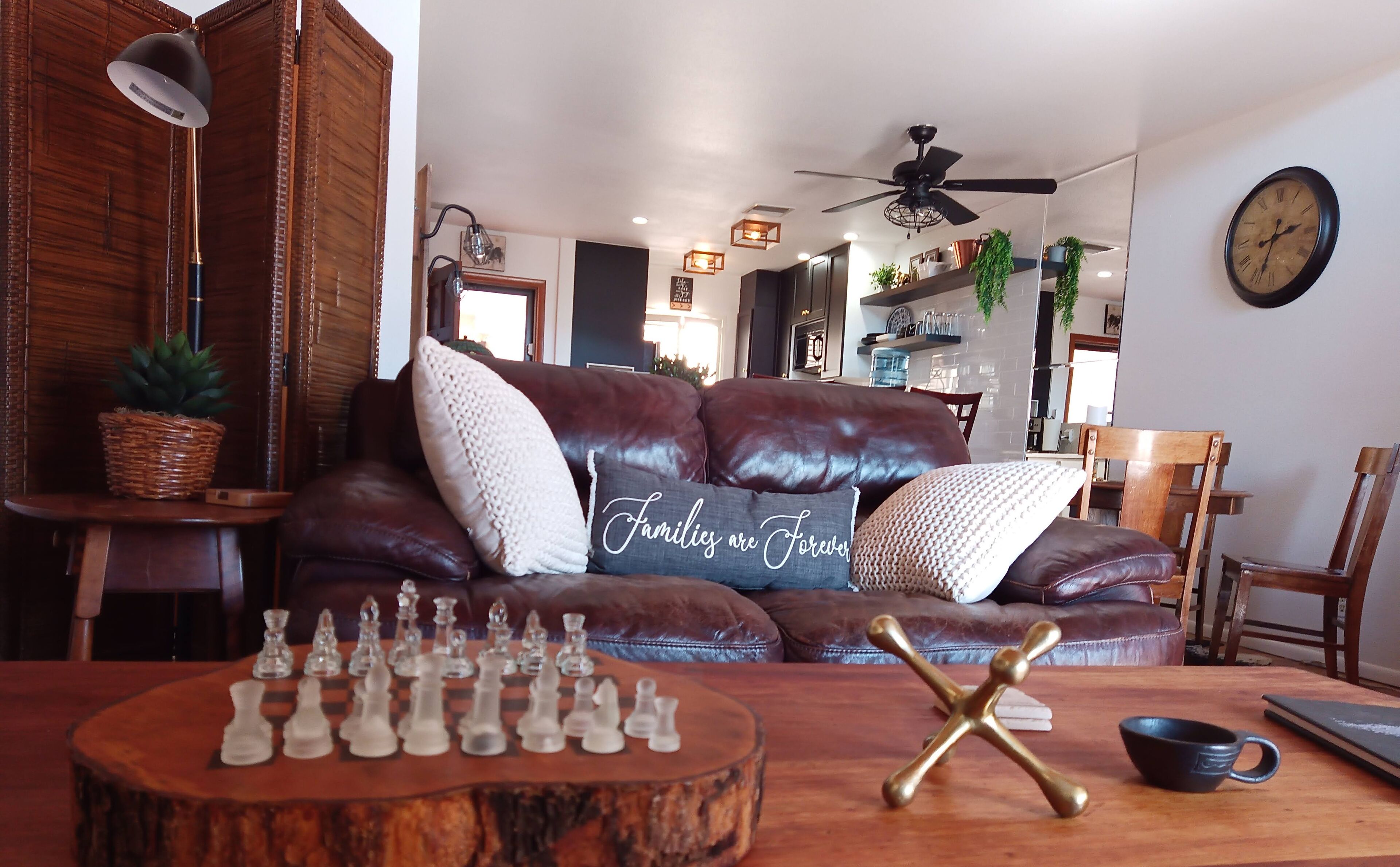 A cozy living room with a leather sofa, a wooden coffee table, and a chessboard.