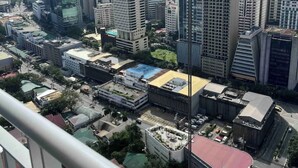 A cityscape with high-rise buildings, a mix of modern and older architecture, and a clear sky. - Your home away from home! (Makati City)