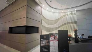 A modern reception area with a curved ceiling, a wooden reception desk, and a wall with vertical slats. There are informational posters on the desk. - Your home away from home! (Makati City)