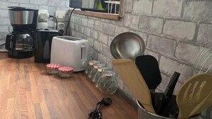 A kitchen with a brick wall, a coffee maker, a toaster, and a kettle. - LA P'TITE MAISON DU CANAL (Drevant)